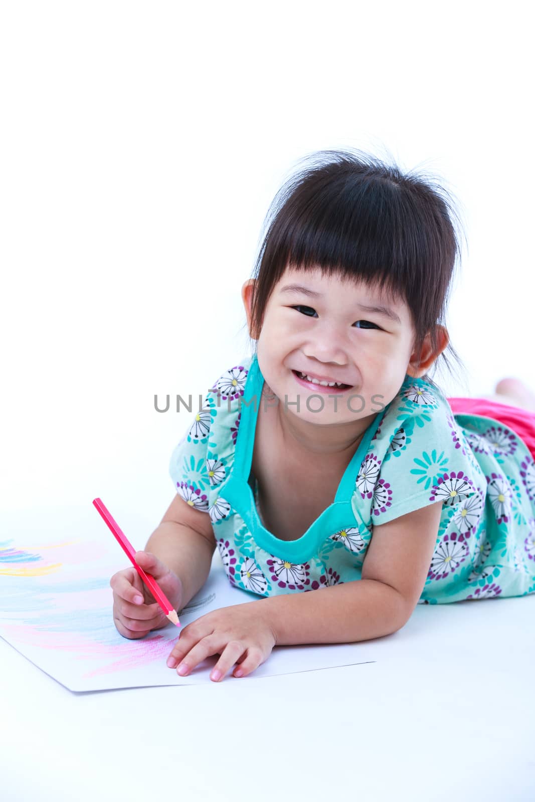 Pretty asian girl lie on the floor looking at camera and smiling. Concepts of creativity and education, strengthen the imagination of child. Studio shot. On white background.