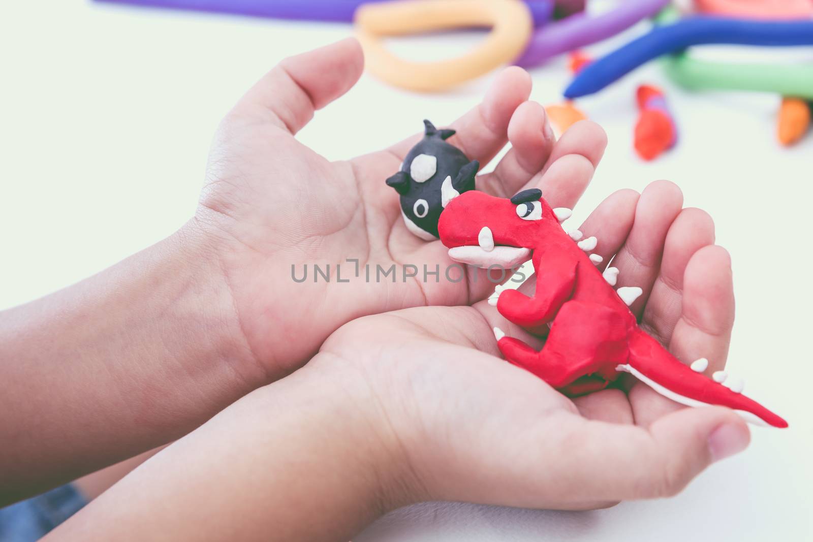 Close up. Creating red dinosaur and whale clay model, on white background. Animals from play dough on child hand. Education concept.