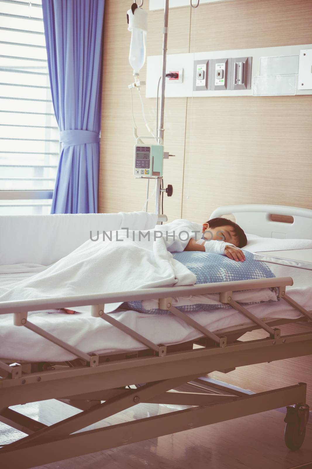 Illness asian boy sleeping on sickbed in hospital with infusion pump intravenous IV drip. Health care and people concept. Shallow depth of field (DOF) saline intravenous (IV) in focus. Vintage style.