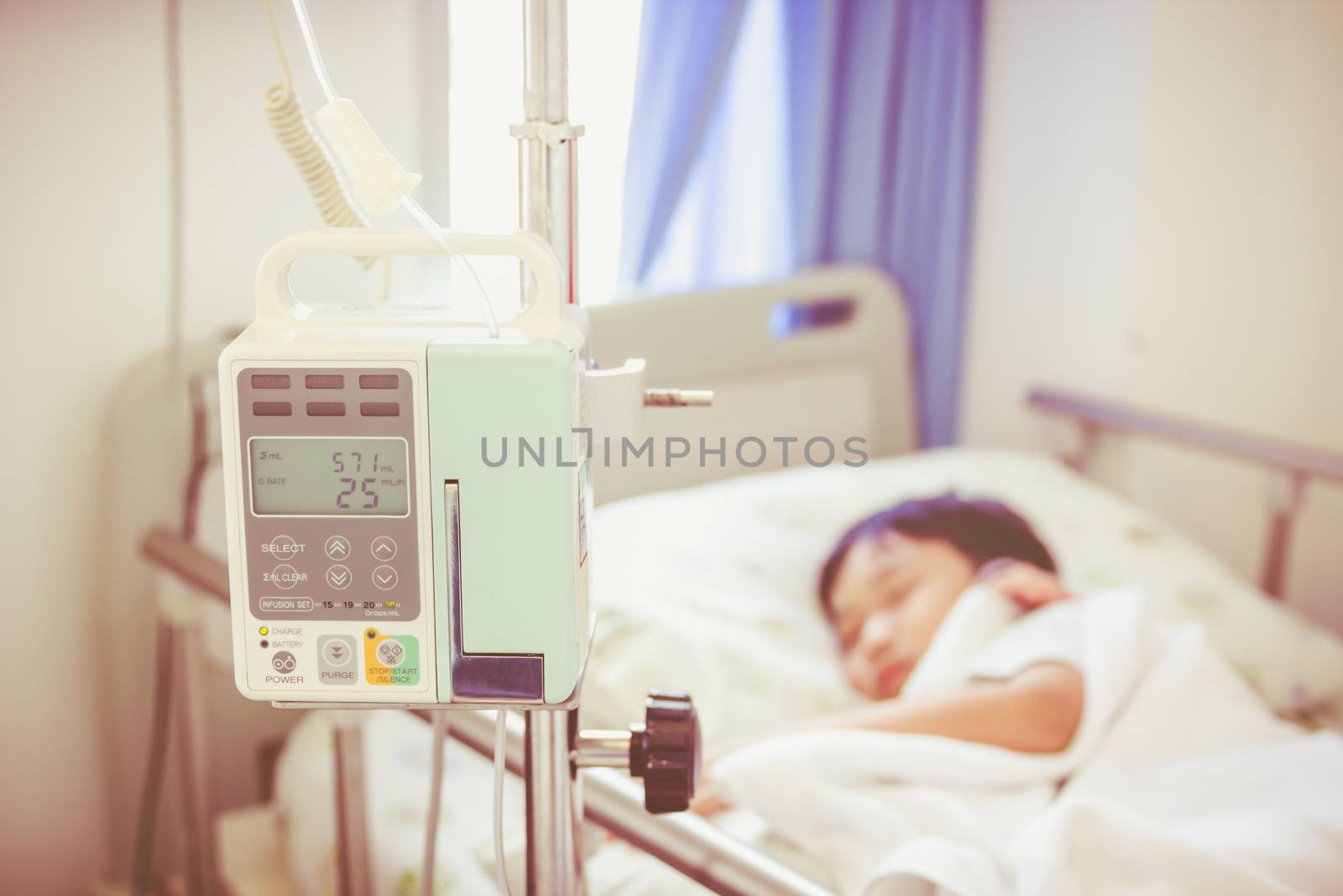 Illness asian boy lying on sickbed in hospital with infusion pump intravenous IV drip. Shallow depth of field, IV machine in focus, child out of focus. Health care and medical concept. Vintage style.