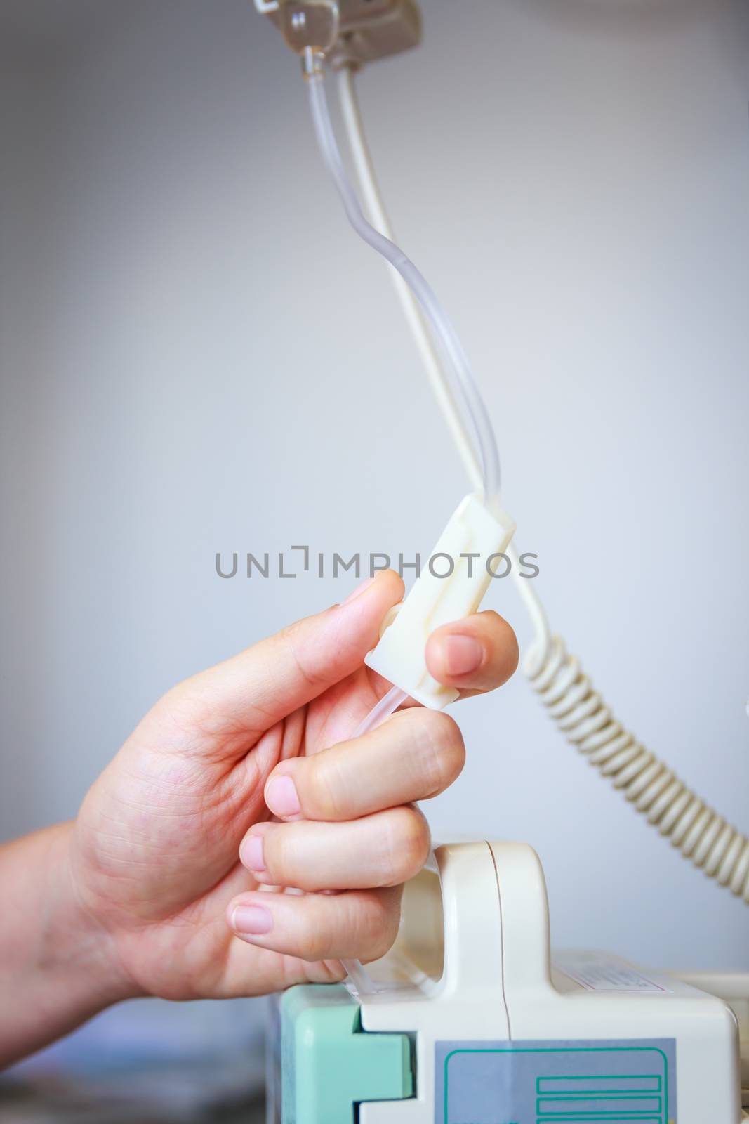 Nurse's hands regulation an intravenous (IV) drip in hospital room. Health care under medical observation. Vignette picture style.