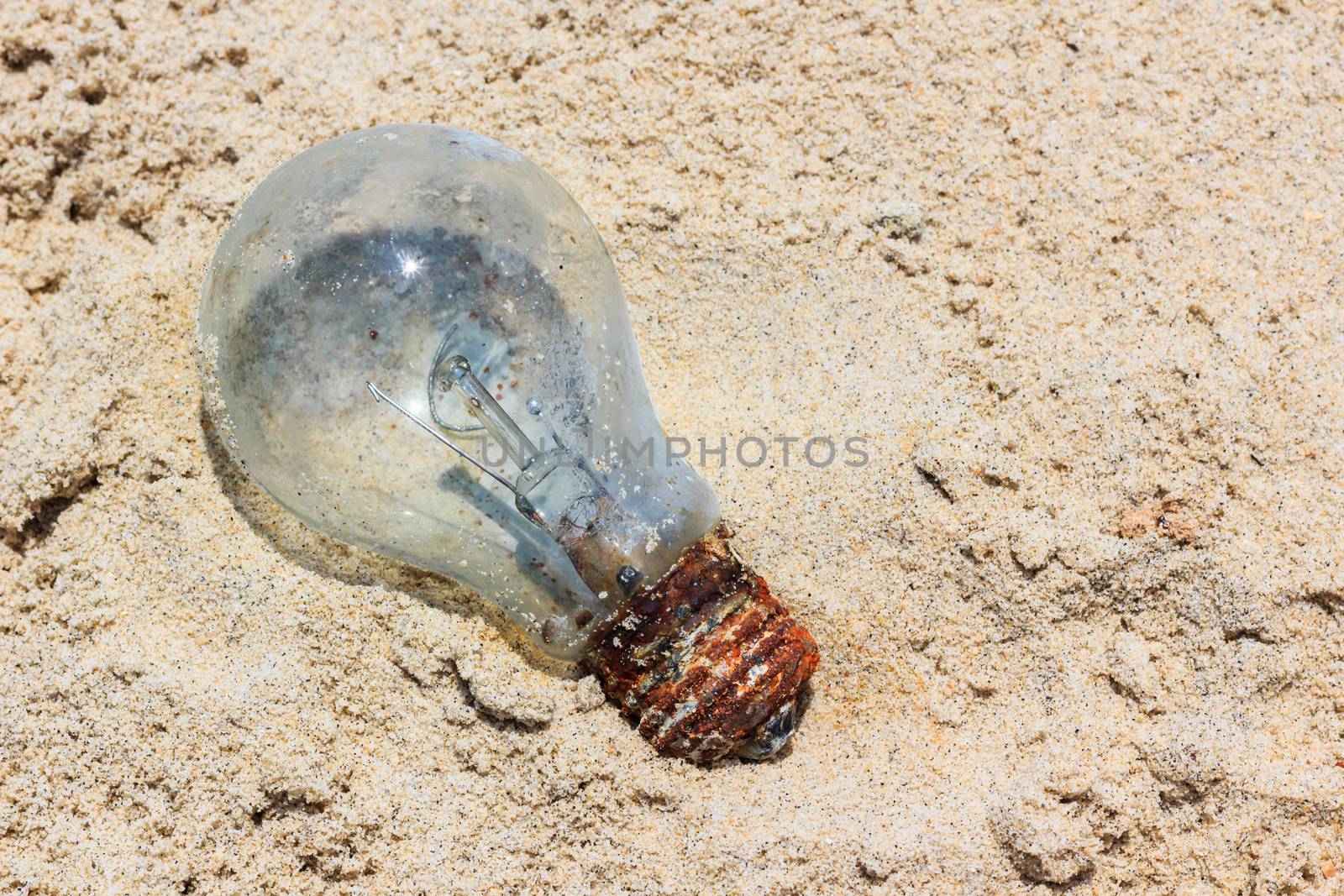 Light bulb was throw away on the beach and free form copy space. Environmental pollution concept picture. Outdoors.