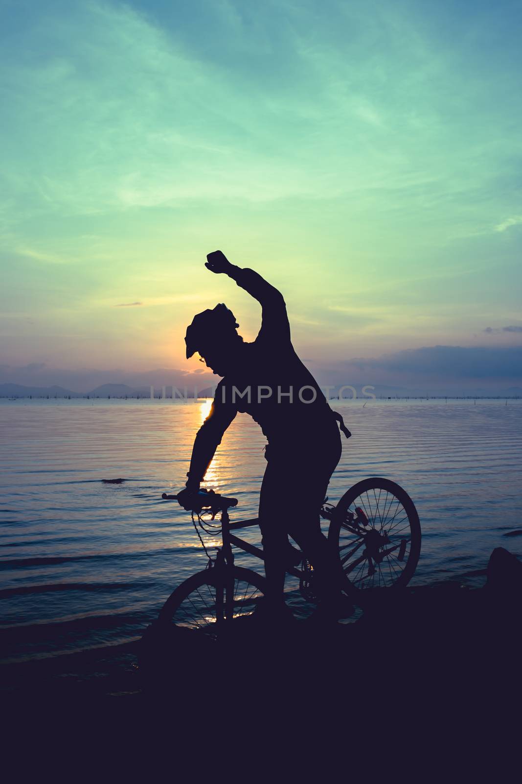 Silhouette of bicyclist riding the bike on rocky trail at seaside, on colorful sunset sky background. Active outdoors lifestyle for healthy concept. Action of winner or successful people.