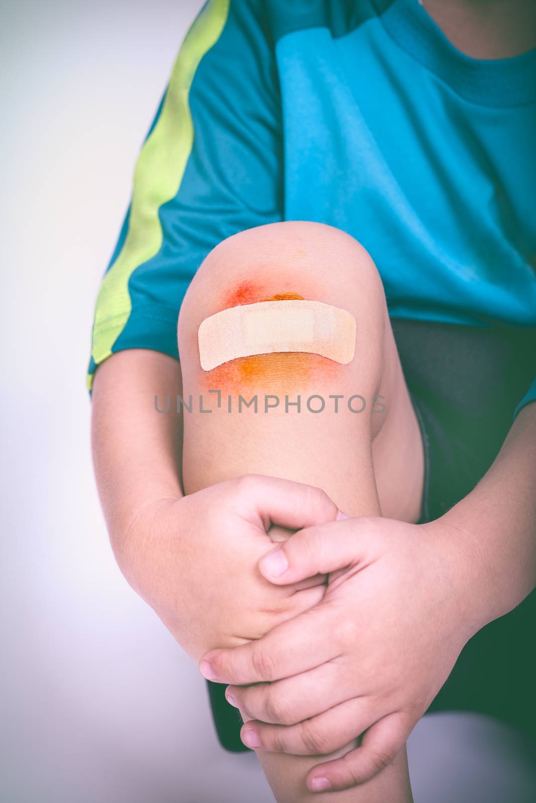 Athlete child injured. Child knee with a plaster and bruise. Selective focus, wound in focus. Human health care and medicine concept. Vintage style.