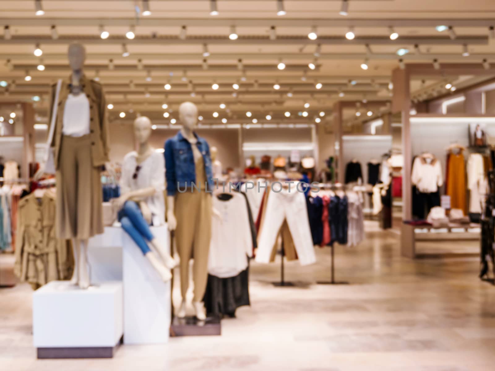 Blur image of dress store with customers and dressed mannequins.