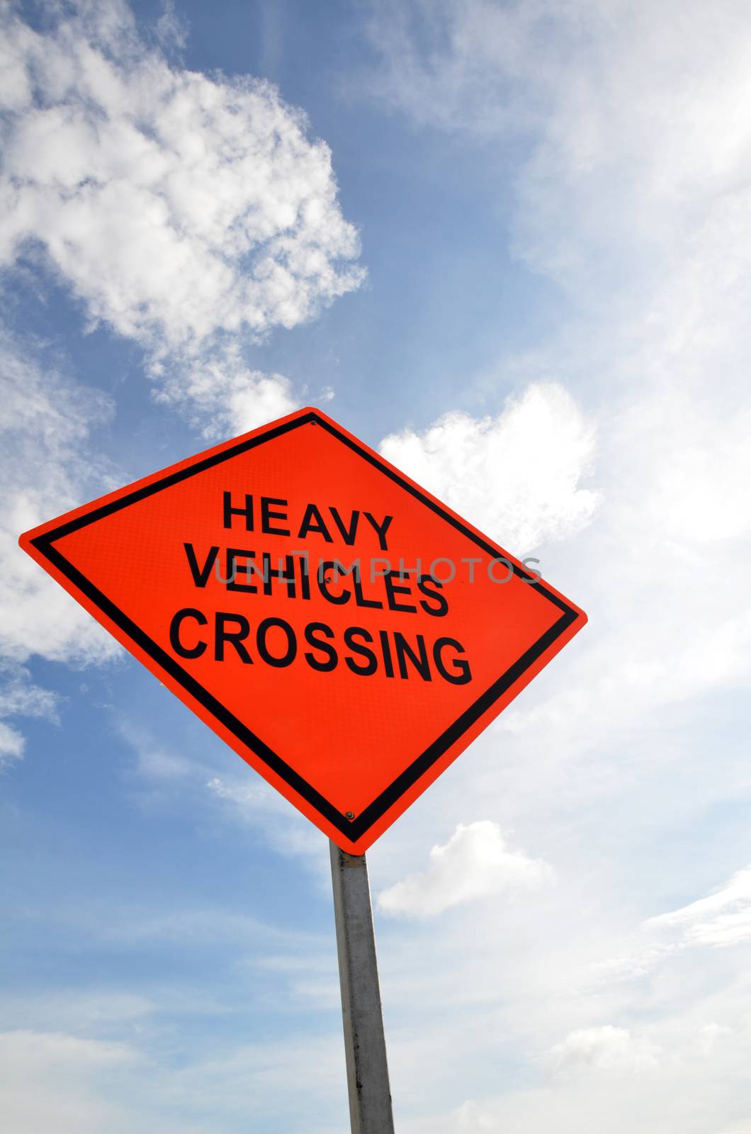 Road sign with a Heavy Vehicles Crossing against a partly cloudy sky background