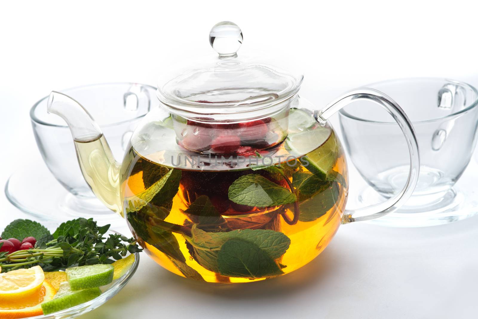 Fruit tea with mint leaves in a teapot on a white background