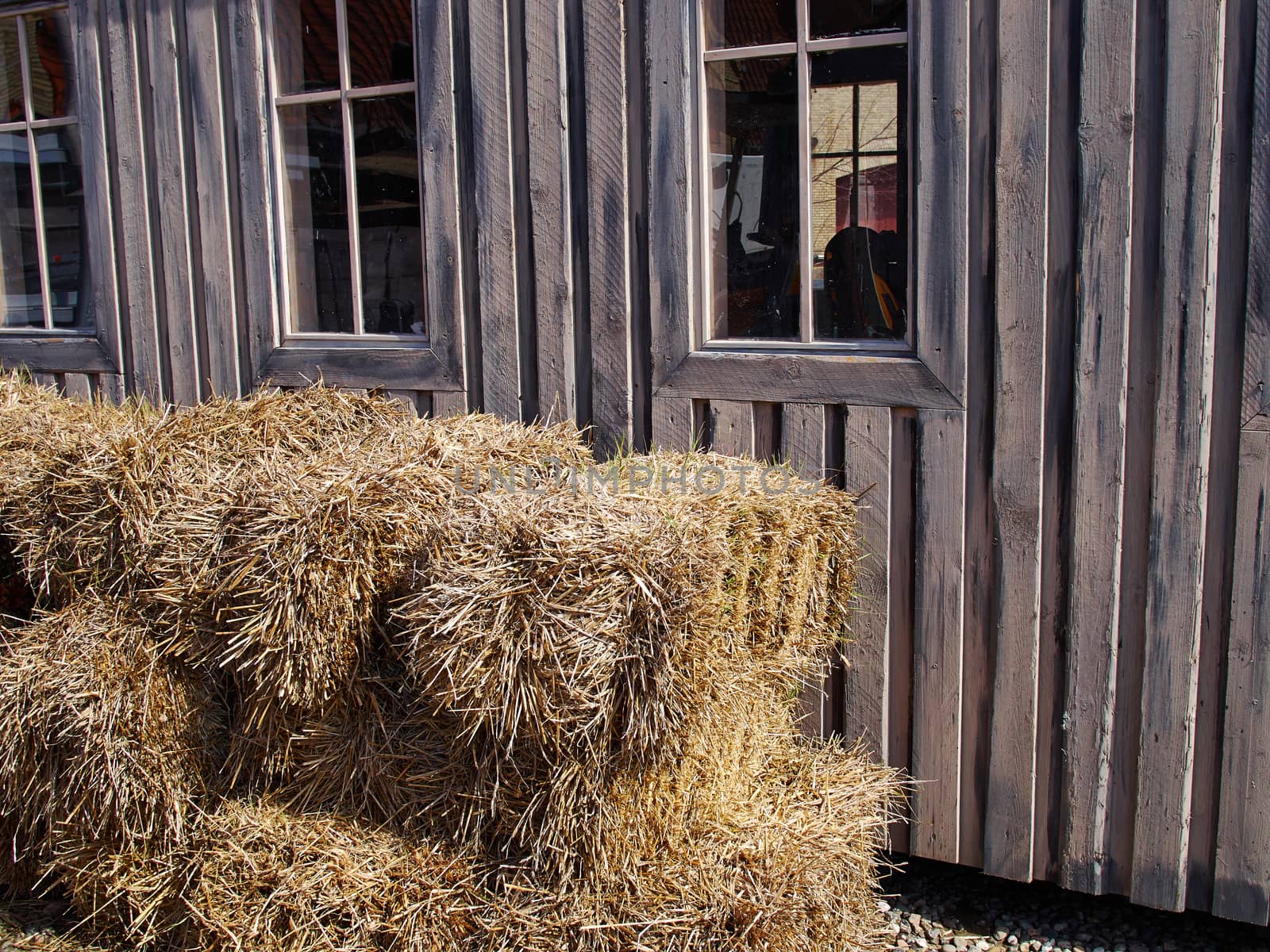Old black wooden barn on a farm with straw hay stacks outside    