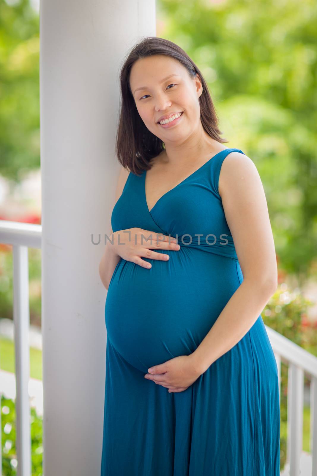 Portrait of Happy Young Pregnant Chinese Woman on the Front Porch.