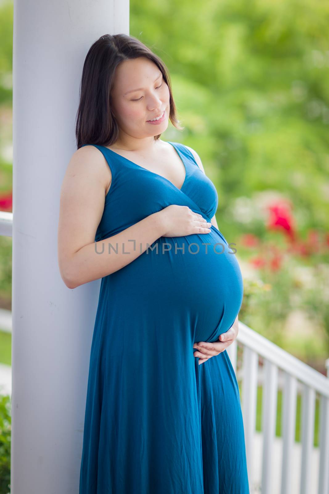 Portrait of Happy Young Pregnant Chinese Woman on the Front Porch.