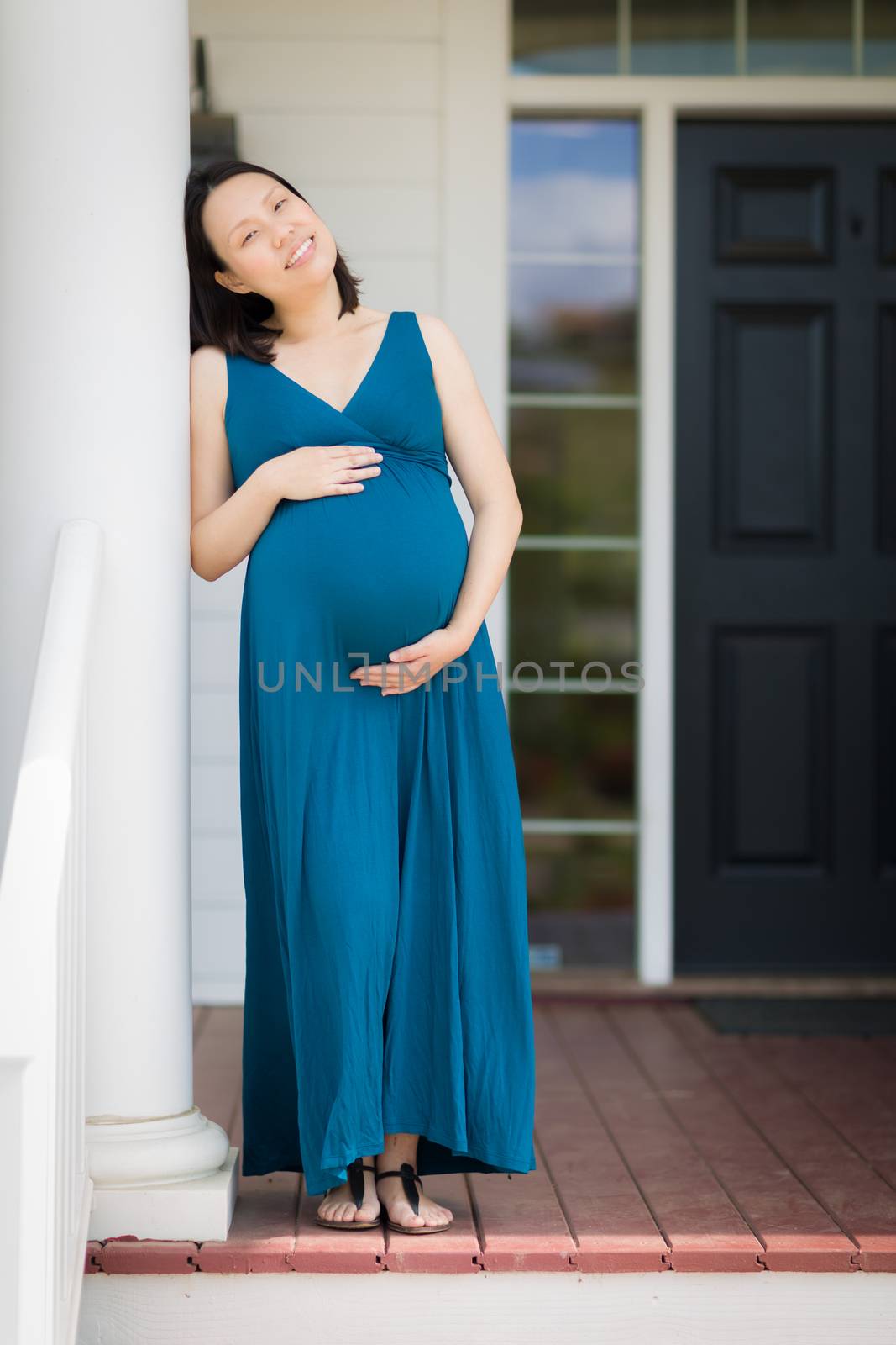 Portrait of Happy Young Pregnant Chinese Woman on the Front Porch.