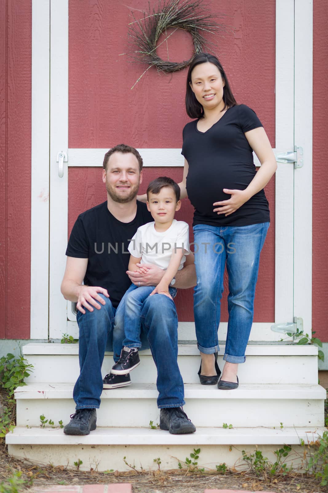 Happy Mixed Race Pregnant Couple with Young Son Portrait.