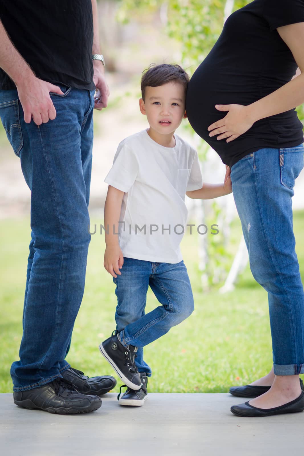 Courious Young Mixed Race Son With Ear on Pregnant Belly of Mommy with Daddy Nearby.