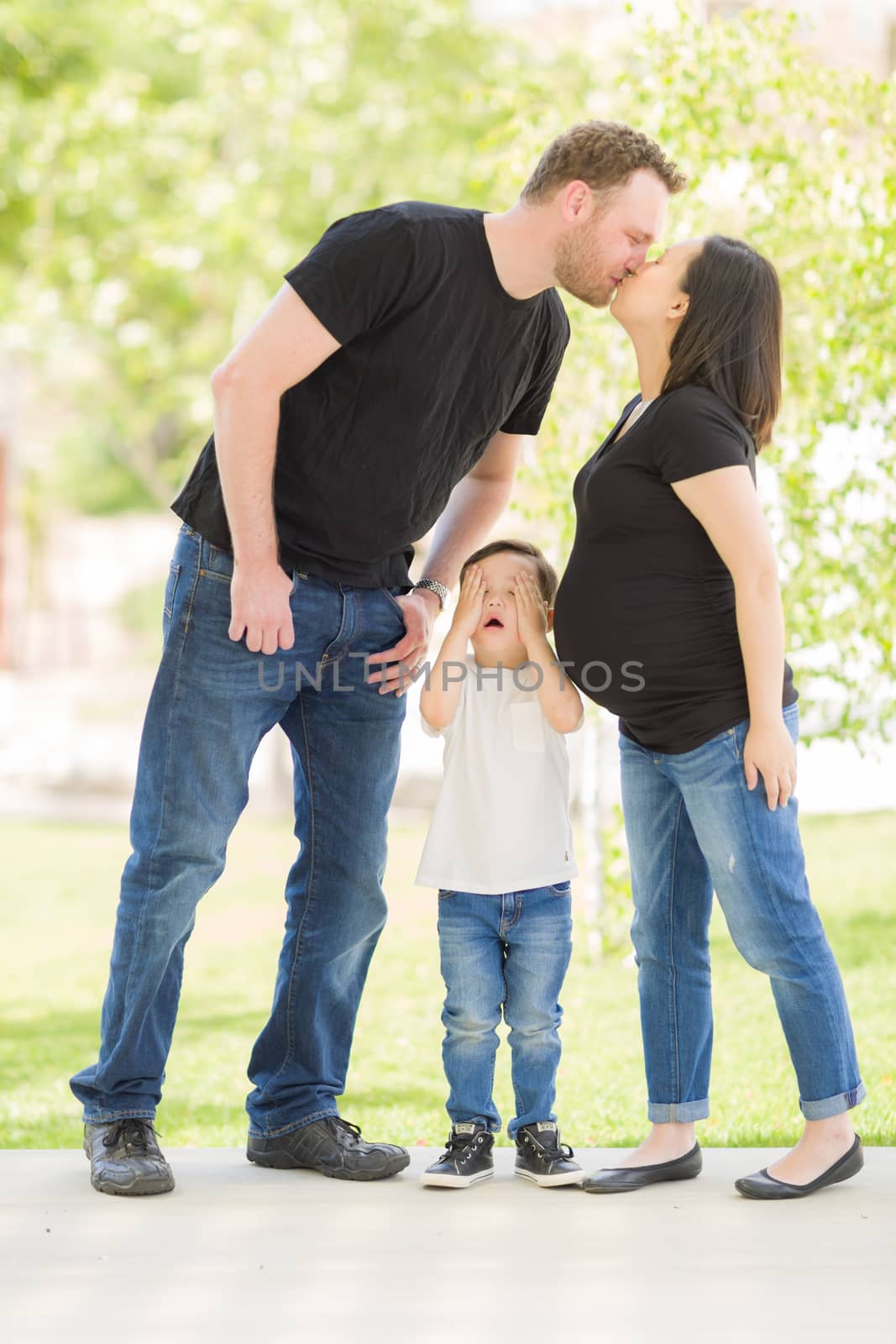 Young Mixed Race Son Hides Eyes as Pregnant Mommy and Daddy Kiss.