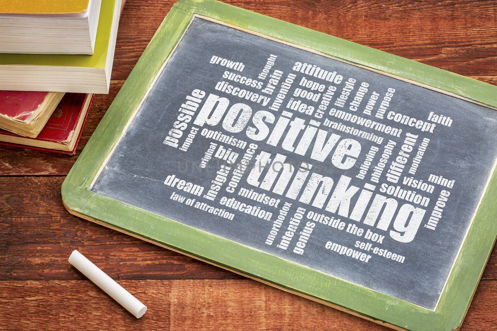 positive thinking word cloud  - white chalk text on a  slate blackboard with a stack of books against rustic wooden table