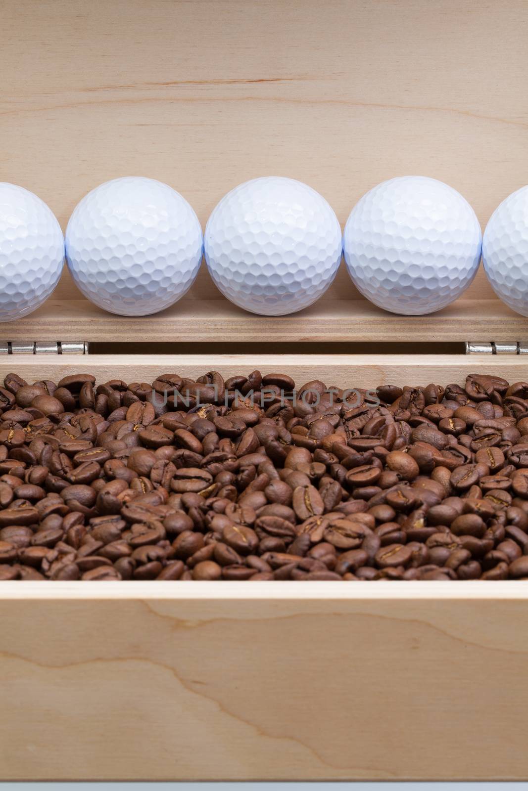 Coffee beans and golf balls in an open box by CaptureLight