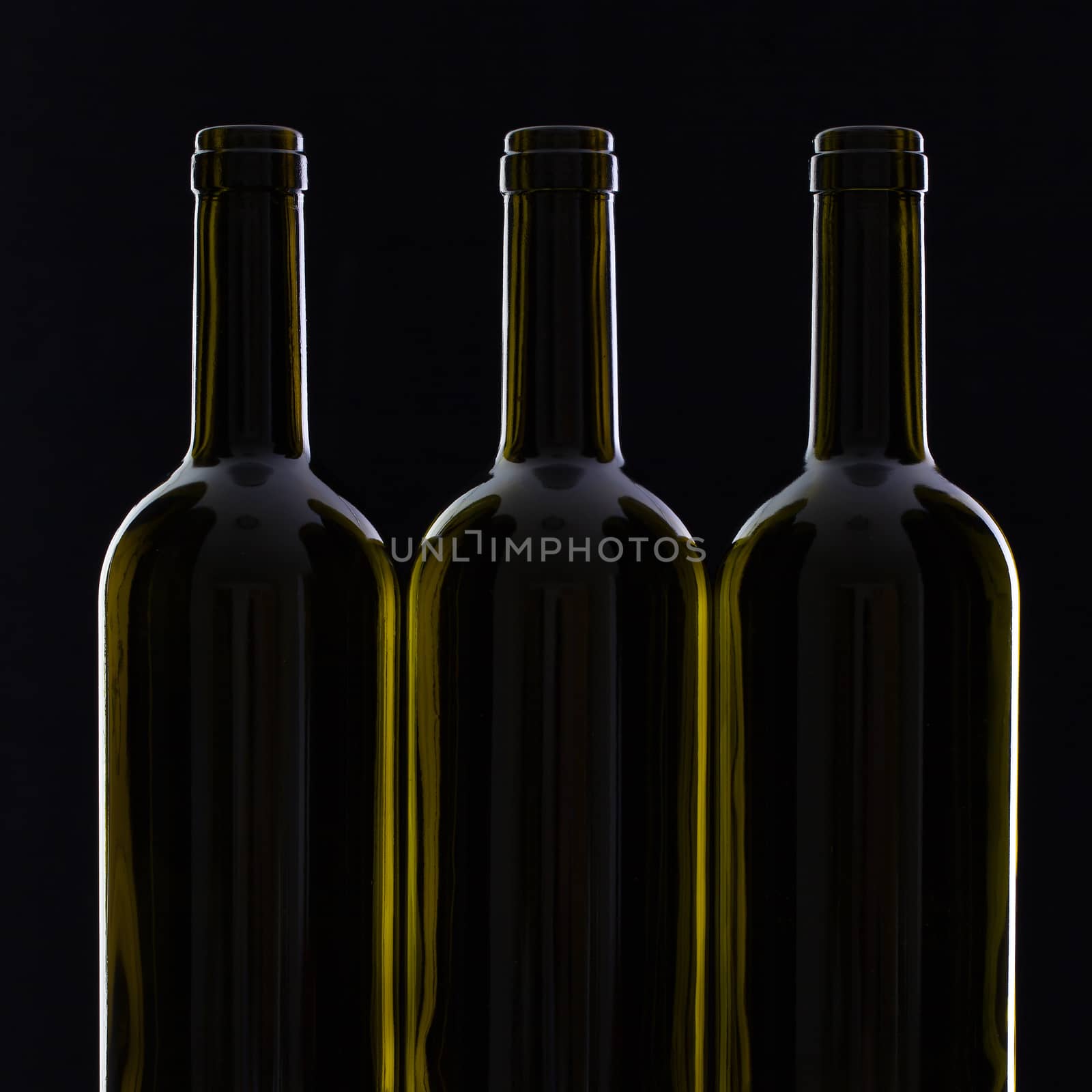 Three different bottles of wine on the black glass.