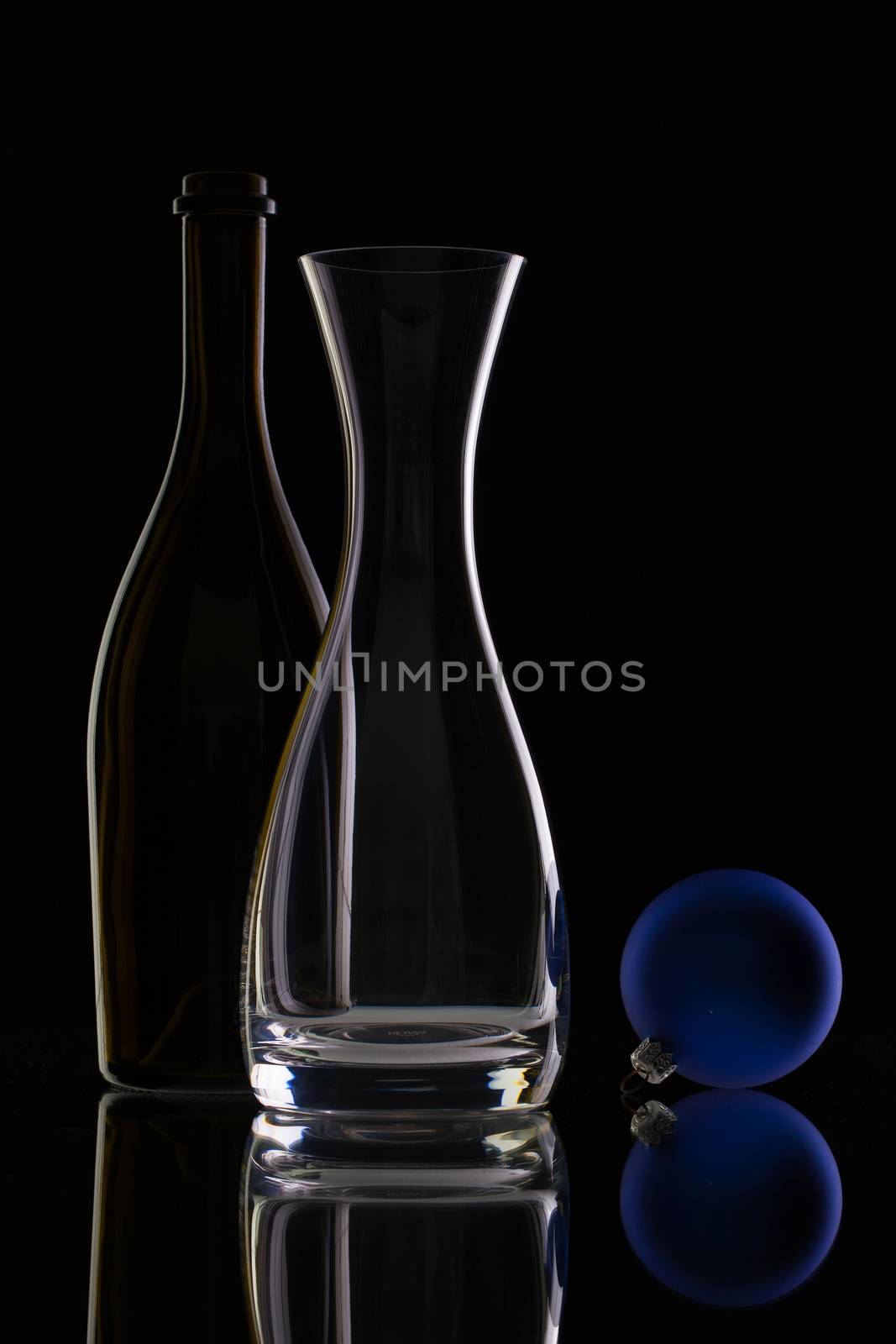 The bottle of wine,glass carafe and Christmas decoration on a black glass desk