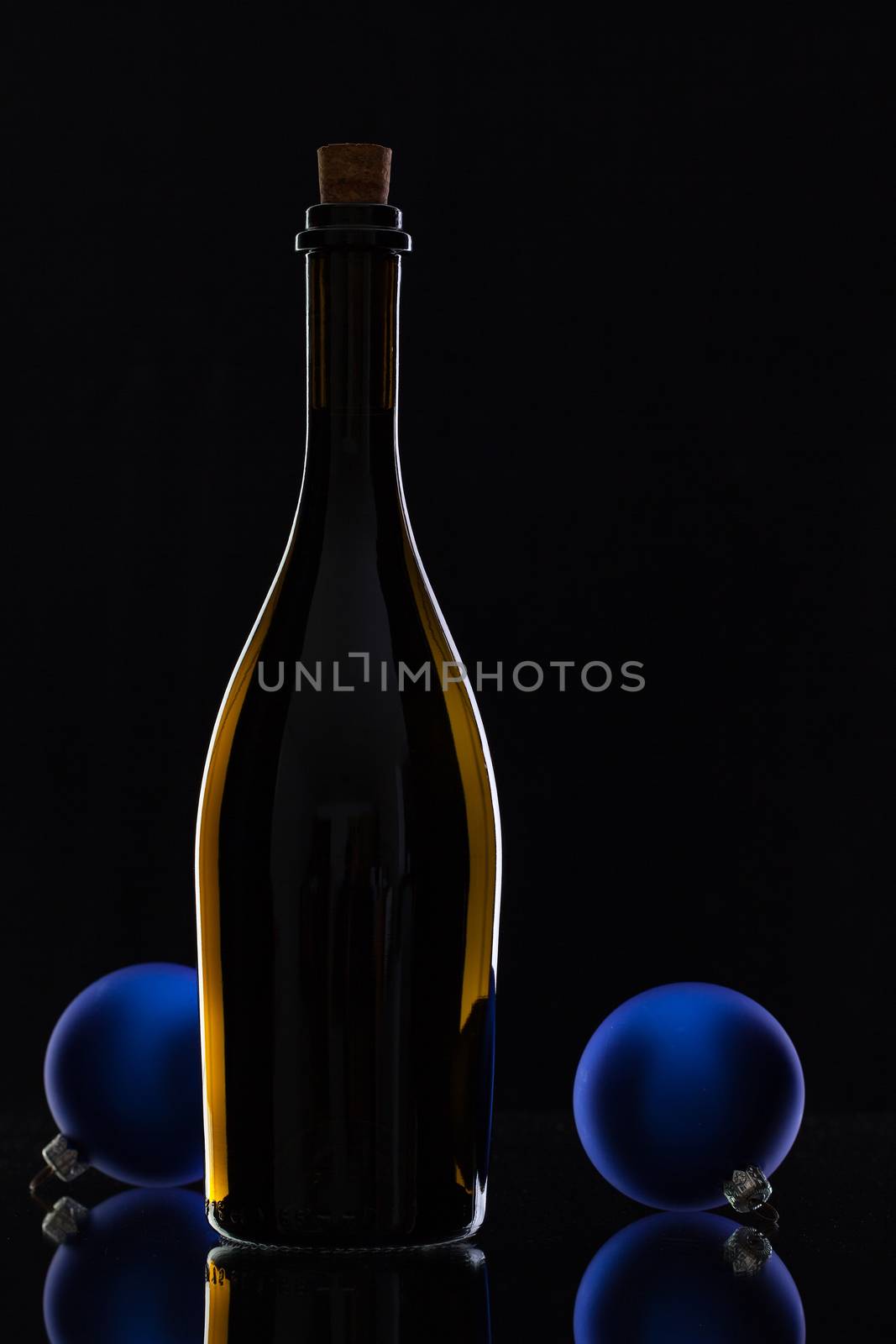 The bottle of red wine and Christmas decoration on a black glass desk
