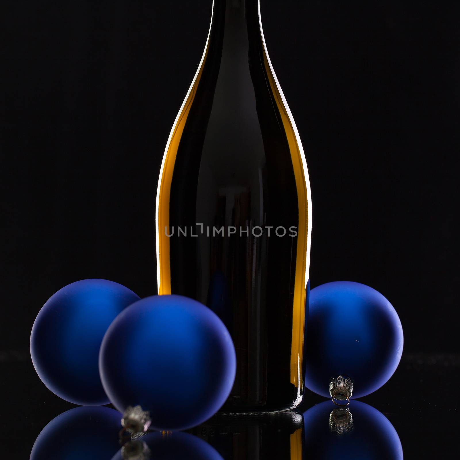 The bottle of red wine and Christmas decoration on a black glass desk