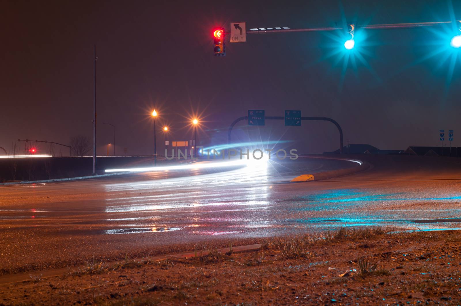 Two Cars creating twisting trails under the stoplight on a rainy night