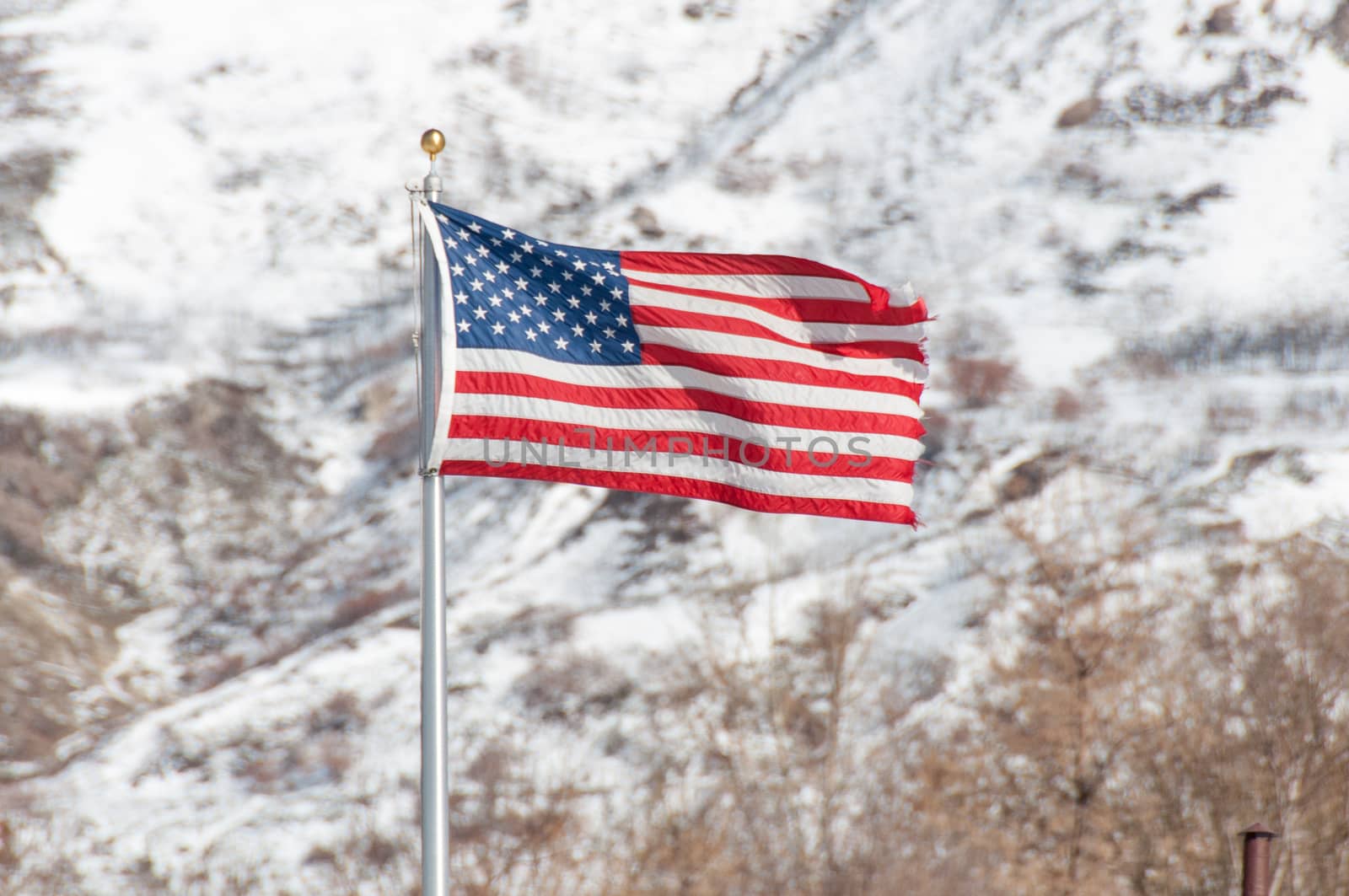 American Flag blowing in the wind while hanging in front of a mountain range