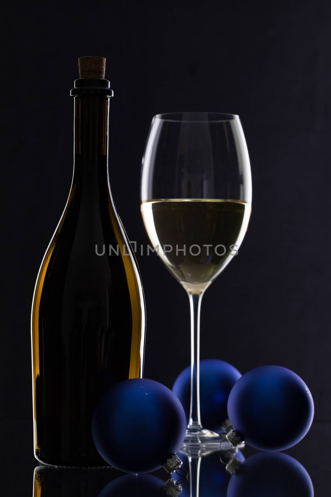 The bottle of white wine and Christmas decoration on a black glass desk