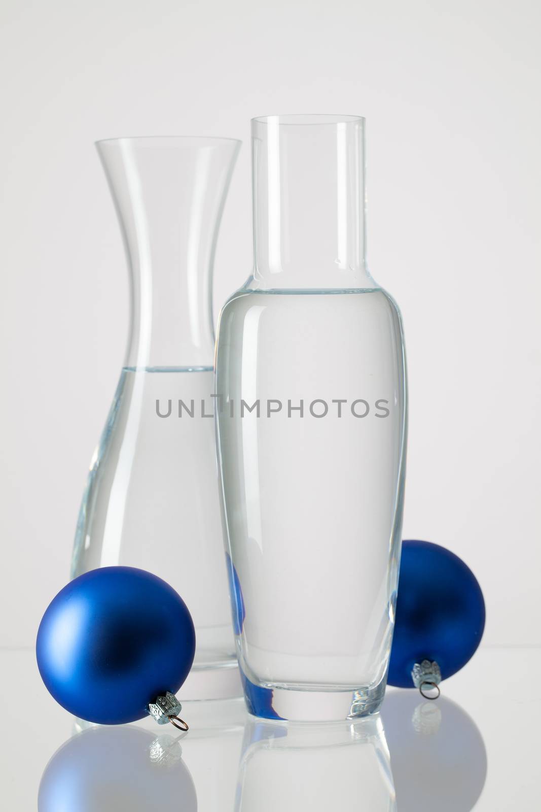 Two vases with clean water and Christmas decoration on a glass table