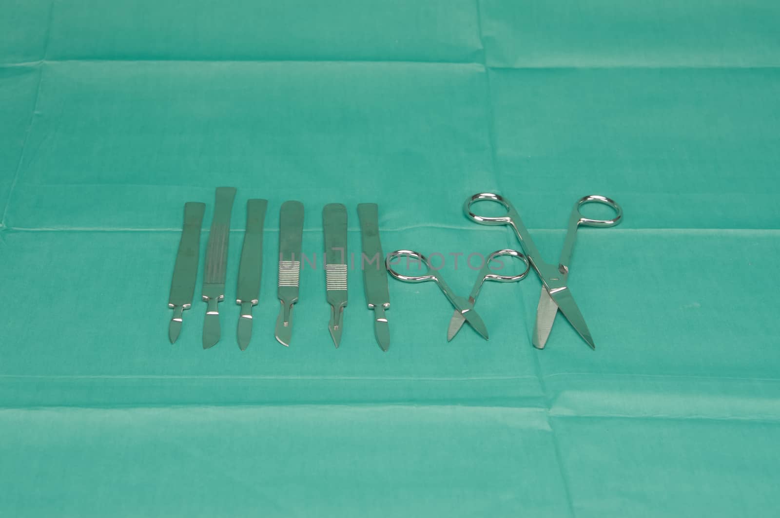 Stainless scalpel and scissors on green fabric by ninun