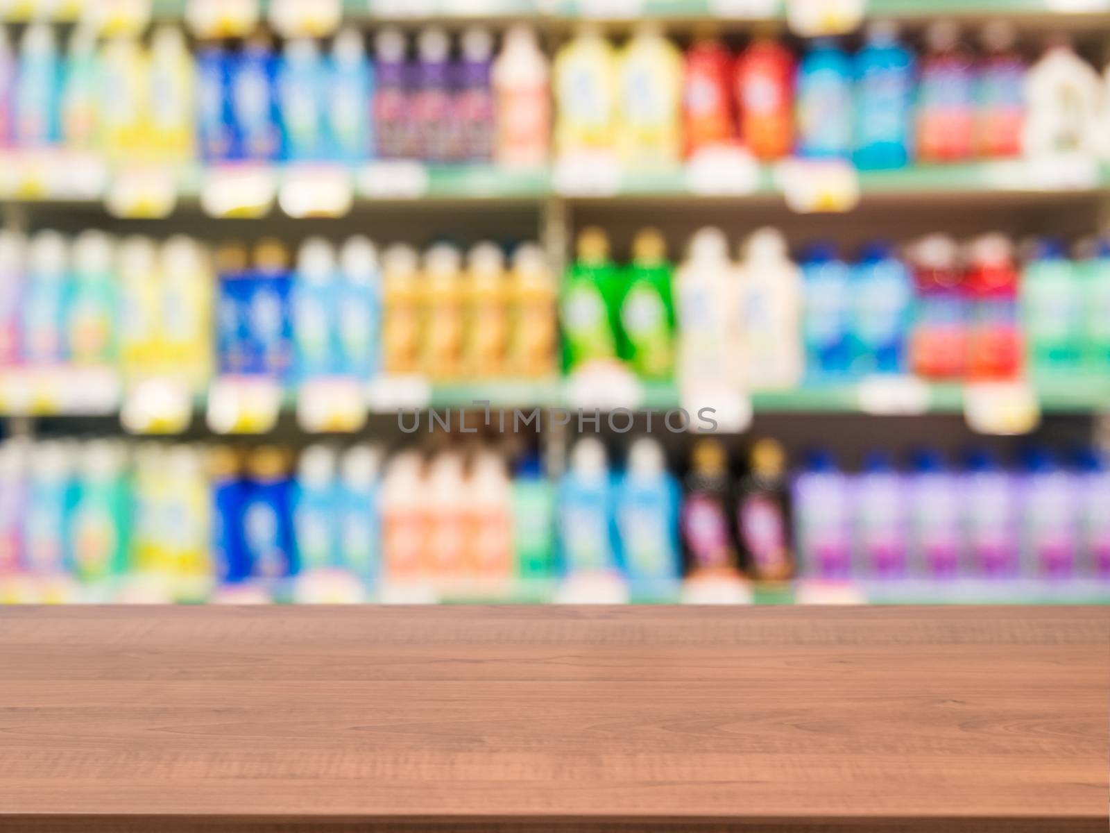 Wooden board empty table in front of blurred background. Perspective dark wood over blur colorful supermarket products on shelves. Mock up for display or montage of product