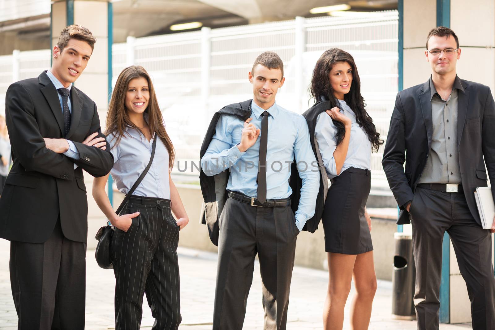 Group of young business people elegantly dressed standing outside.