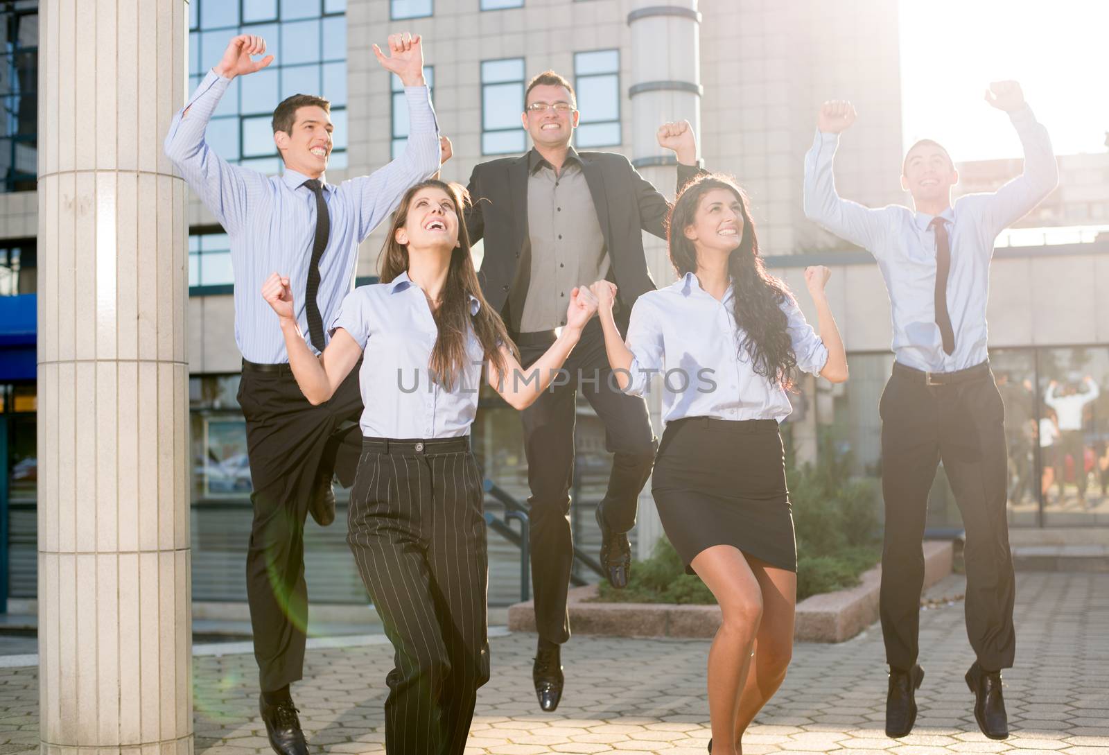 Group of young business people jumping in front of the company celebrating a successful job.