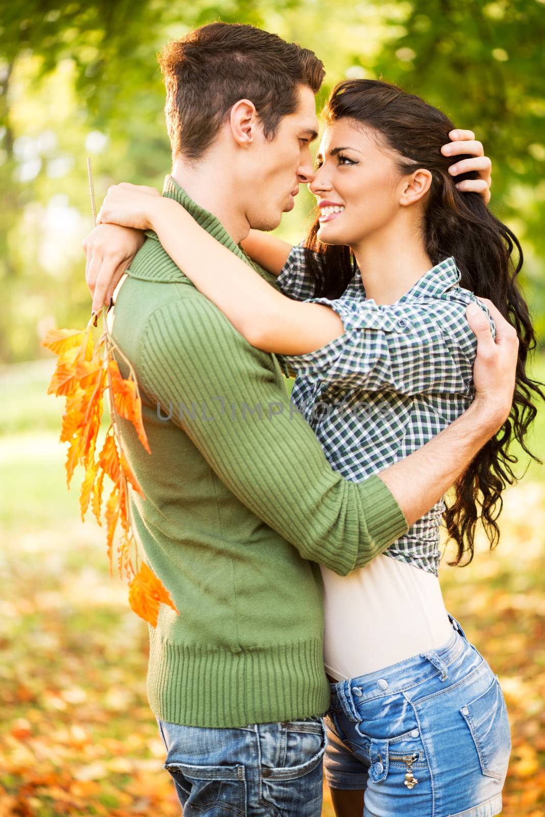Young heterosexual couple embracing standing in the park.