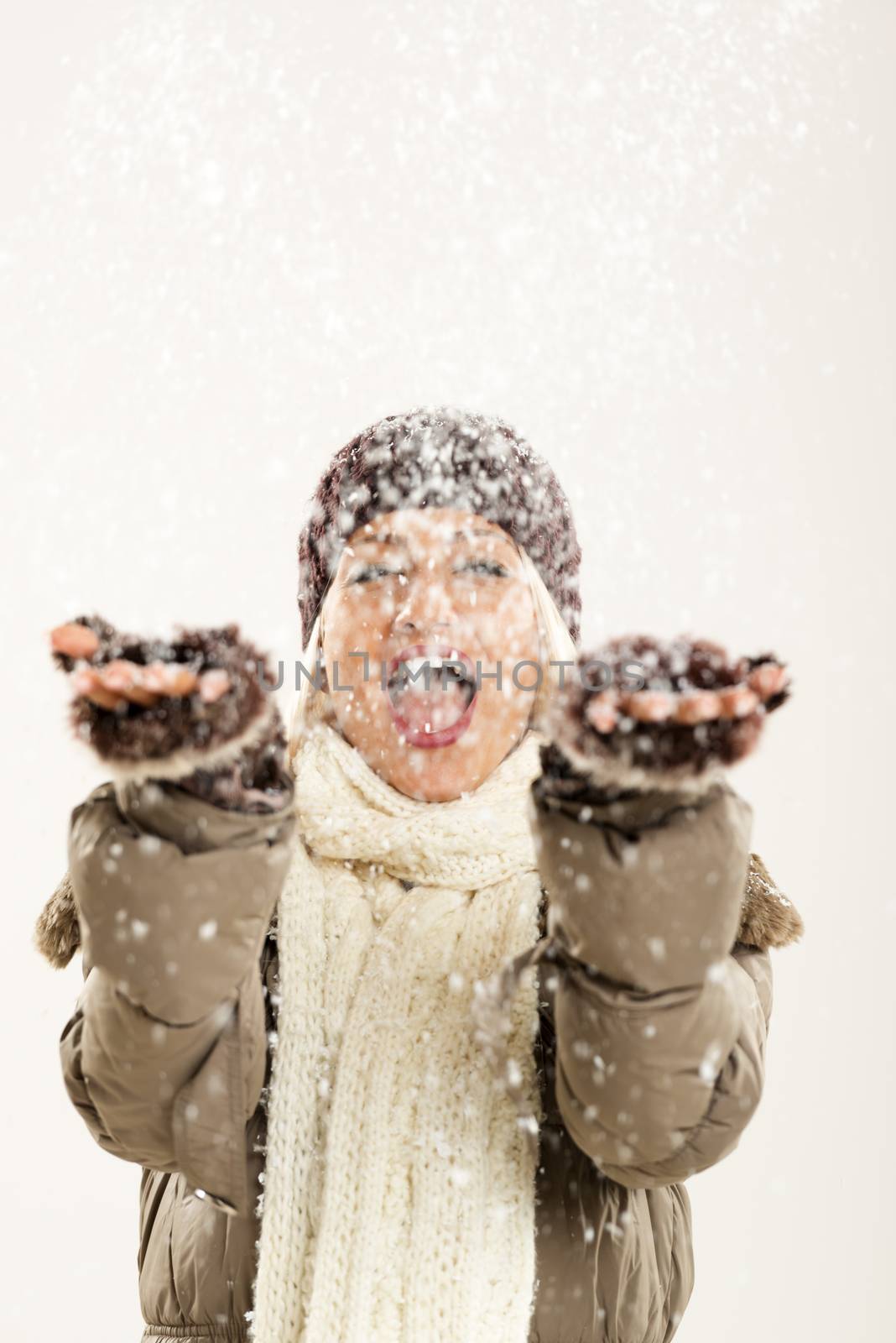 Young cheerful girl In winter clothes with hands outstretched catches snowflakes, rejoicing in the first snow.