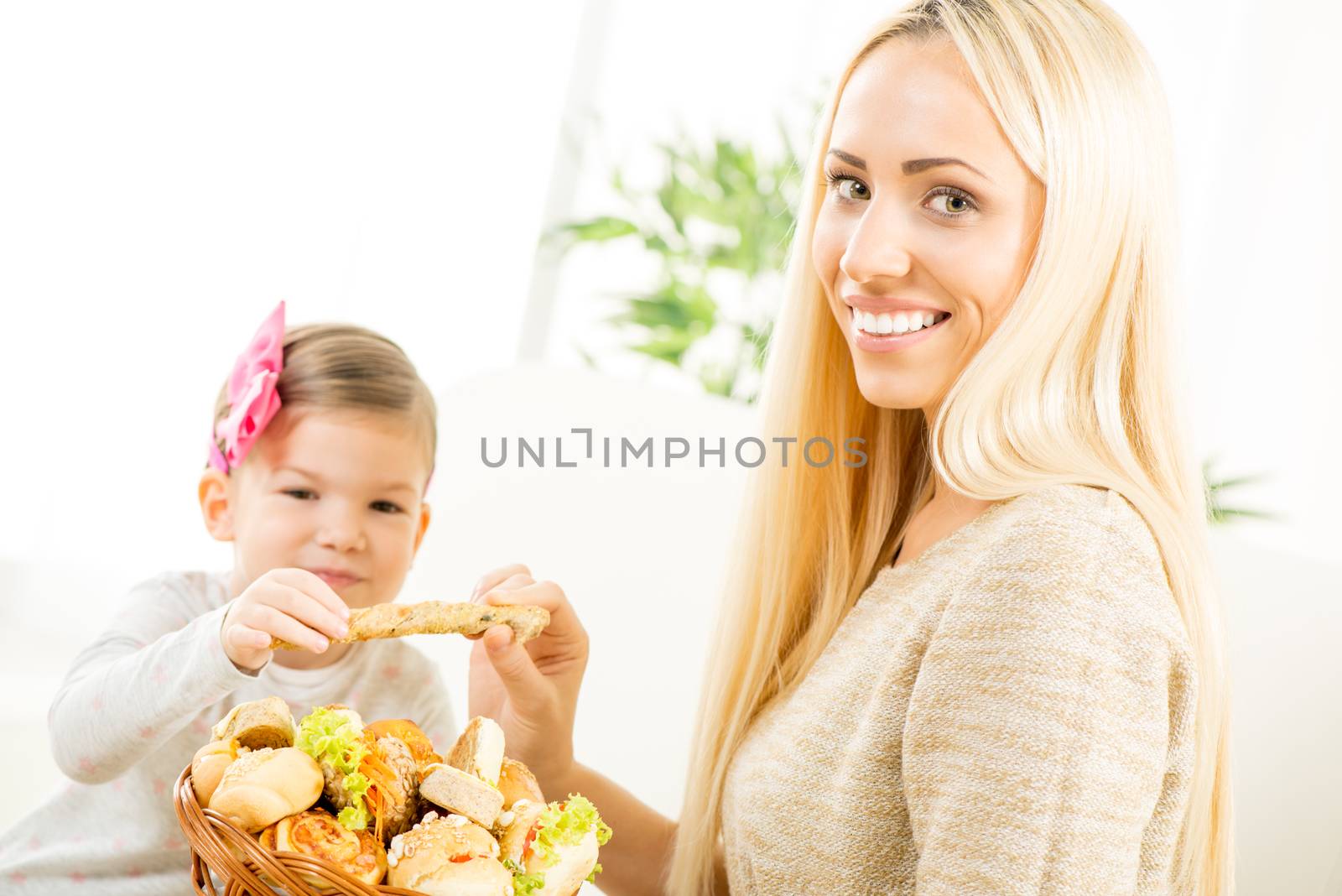 Beautiful mother gives a wicker basket with fresh  bakery products her daughter. With a smile looking at the camera.