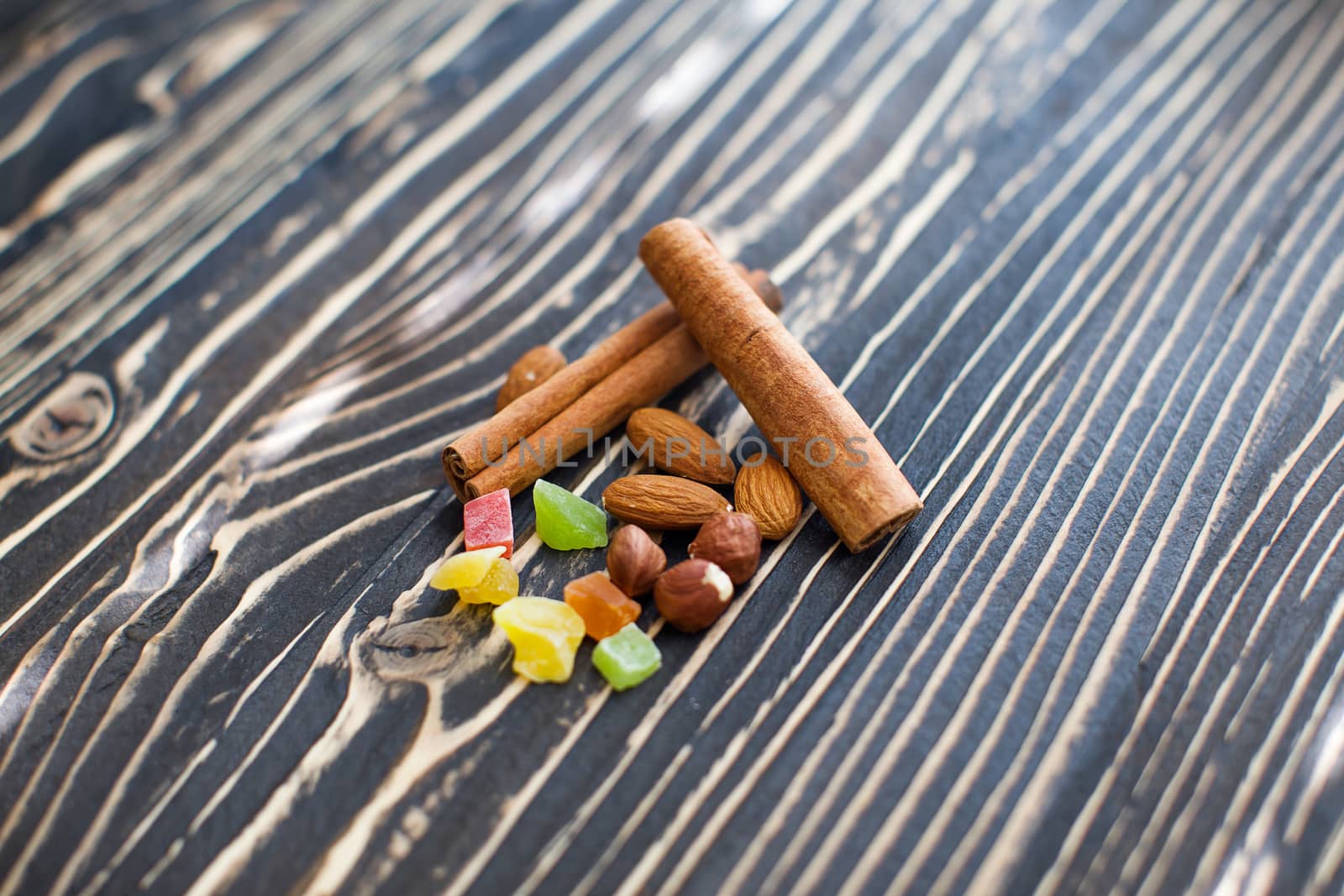 Nuts, candied fruits, cinnamon lie on a textured board