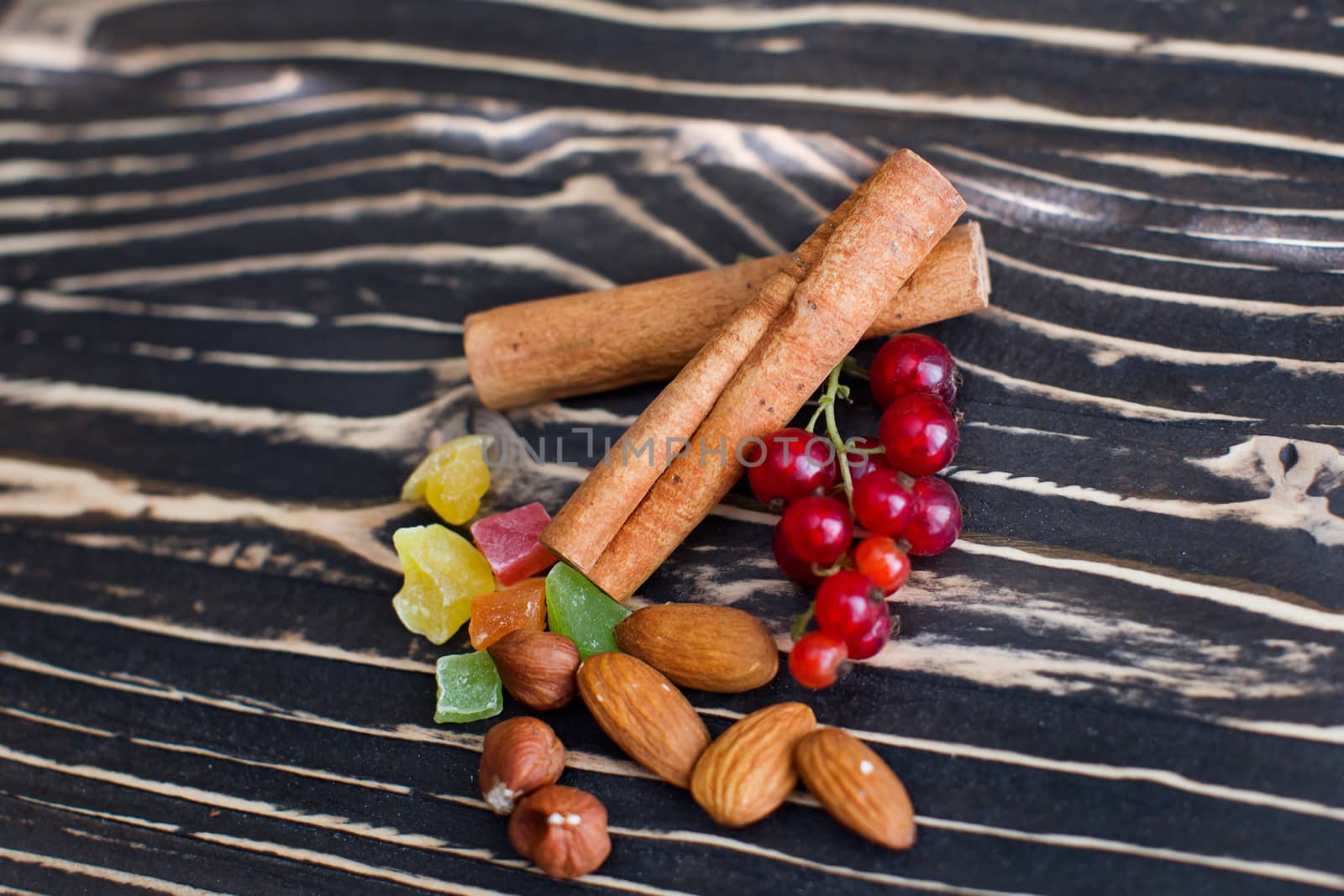 Nuts, candied fruits, cinnamon lie on a textured board
