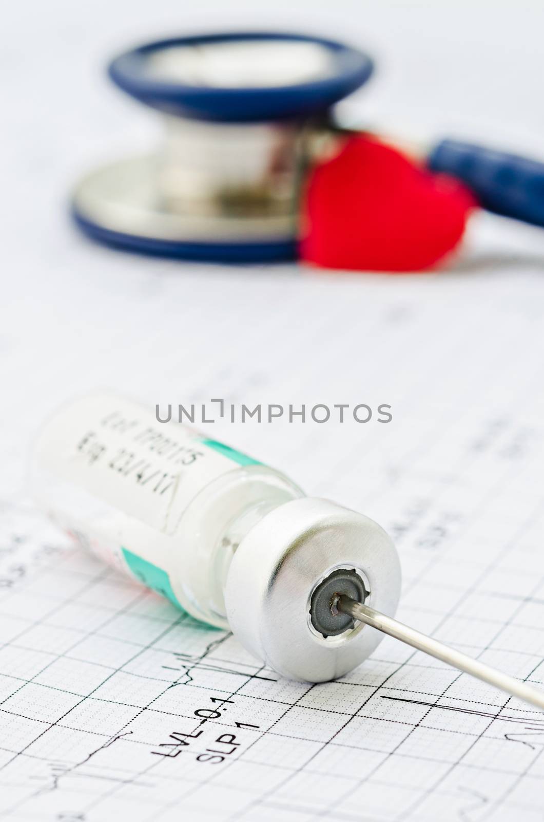 medical ampoules and needle with stethoscope on cardiogram.