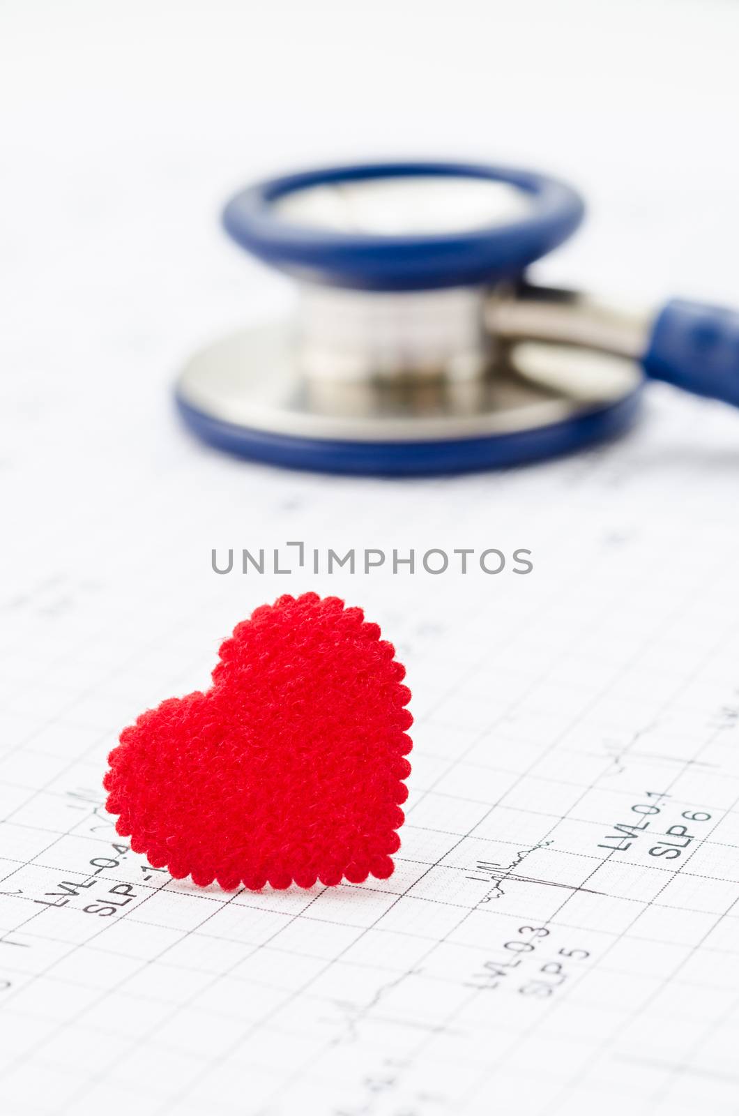 Cardiogram chart with medical stethoscope and small red heart on table closeup