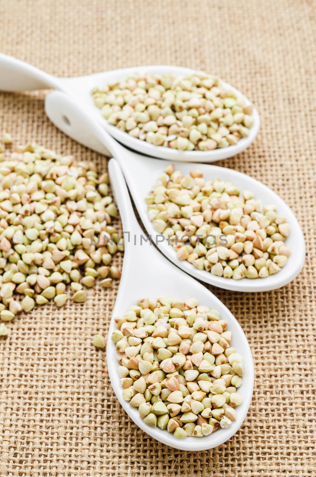 Buckwheat groats in white spoon. by Gamjai