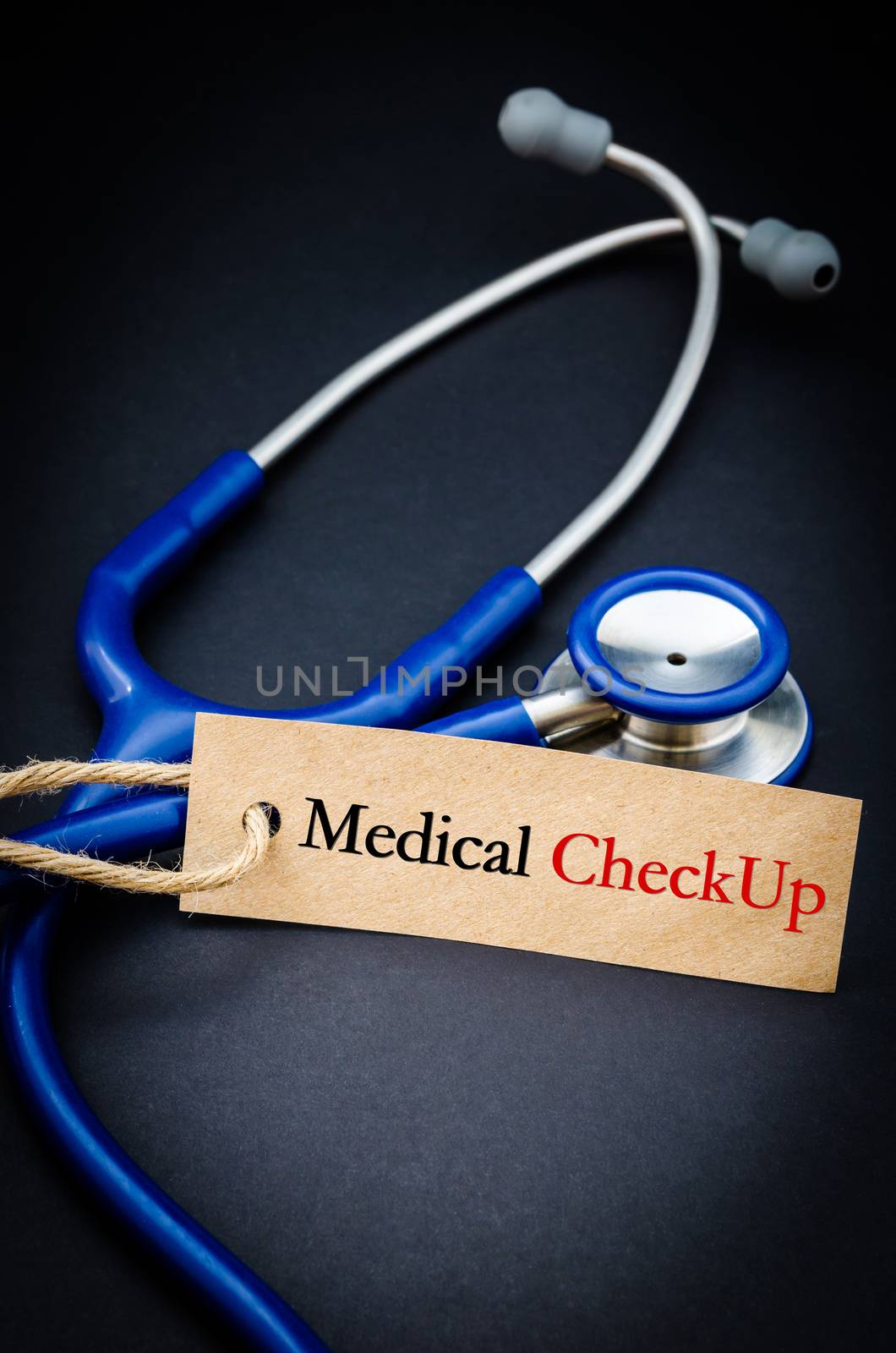 Medical check up word in paper tag with stethoscope on black background - health concept. Medical conceptual