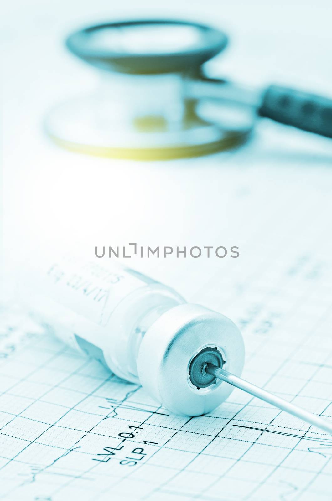 medical ampoules and needle with stethoscope on cardiogram.