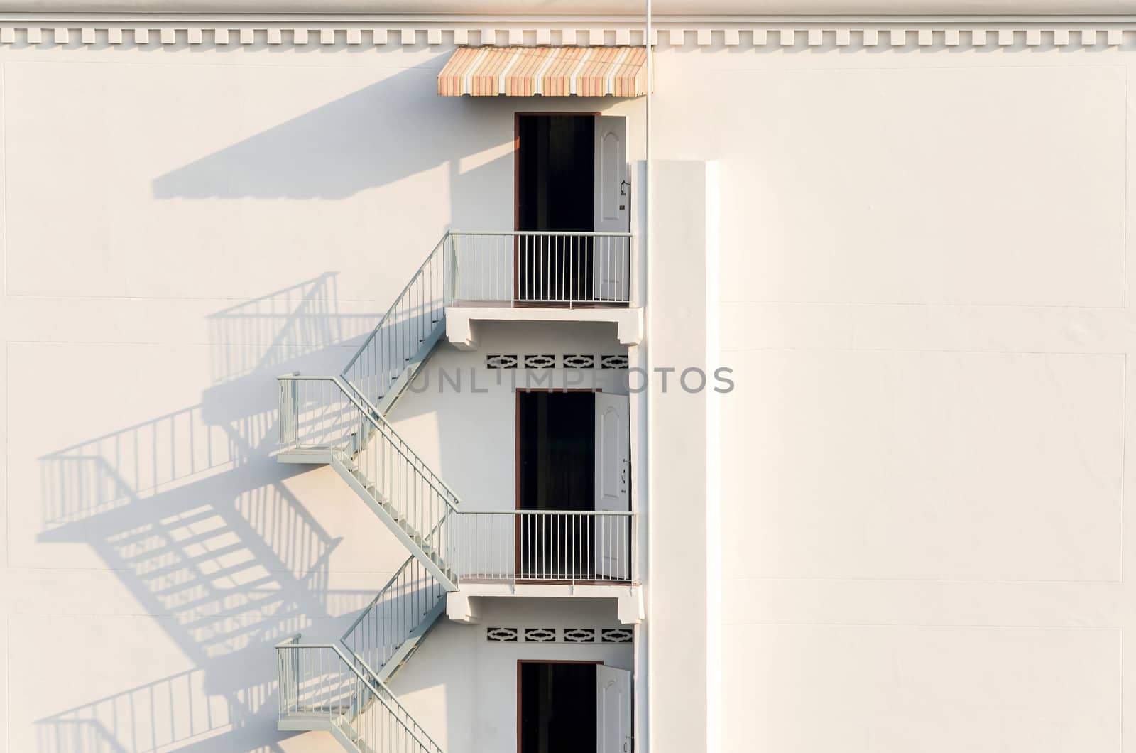 fire escape with afternoon shadows on exterior wall. by koson