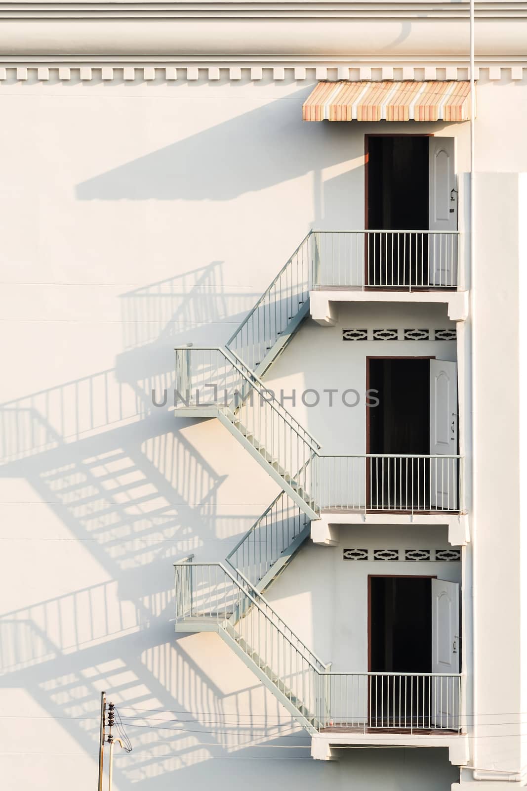 fire escape with afternoon shadows on exterior white wall.