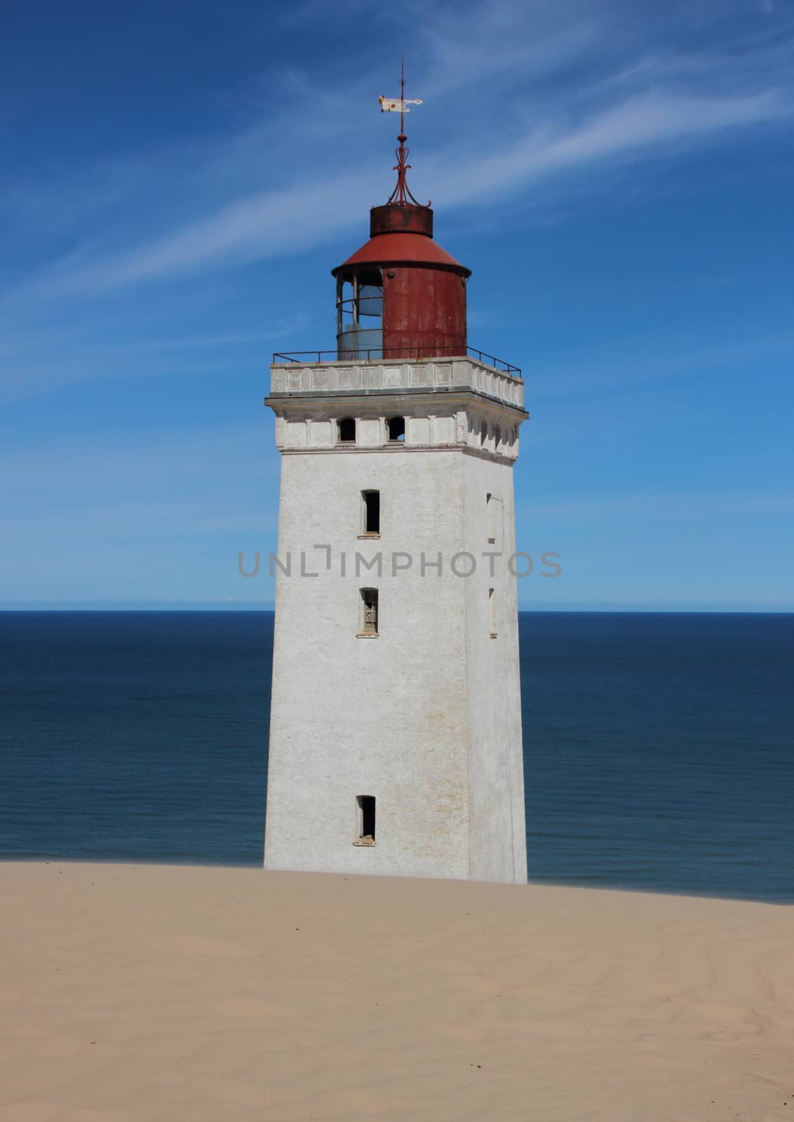 Old Lighthouse with Sand Dune and Blue Ocean in Horizon