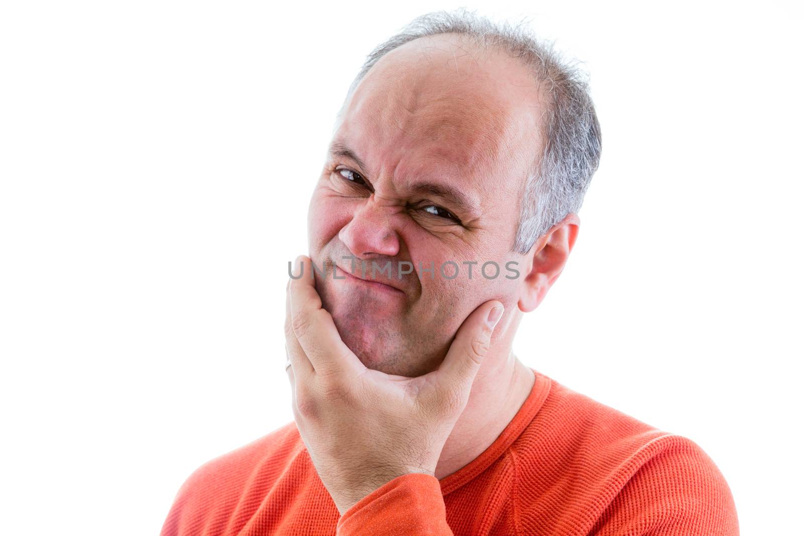 Man feeling ashamed and sorry for something he has done holding his hand to his chin and grimacing as he looks at the camera, head and shoulders on white