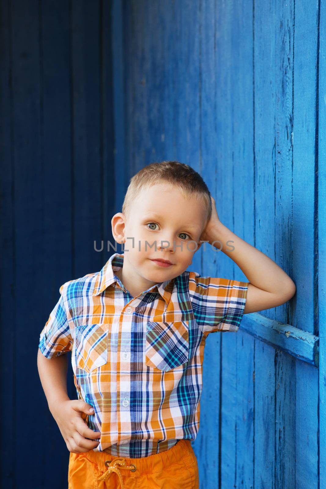 Portrait of happy joyful beautiful little boy against the old textured blue wall