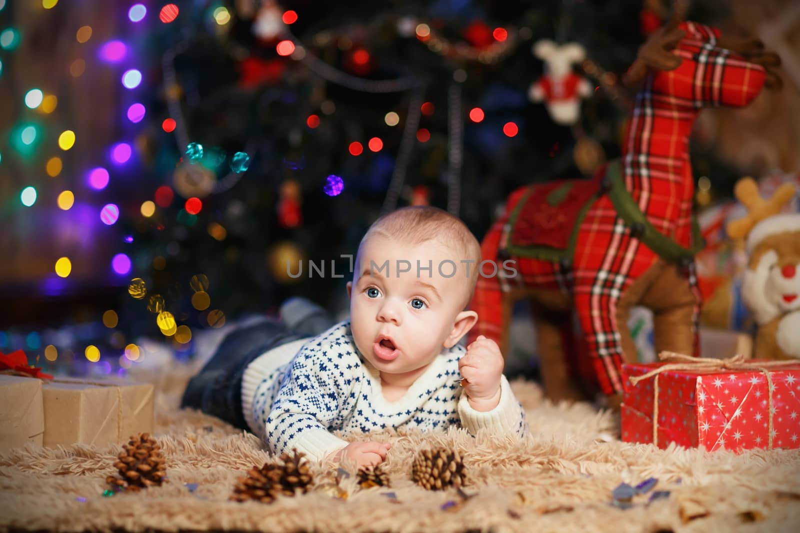 little baby boy lying on his stomach in the room with Christmas decorations