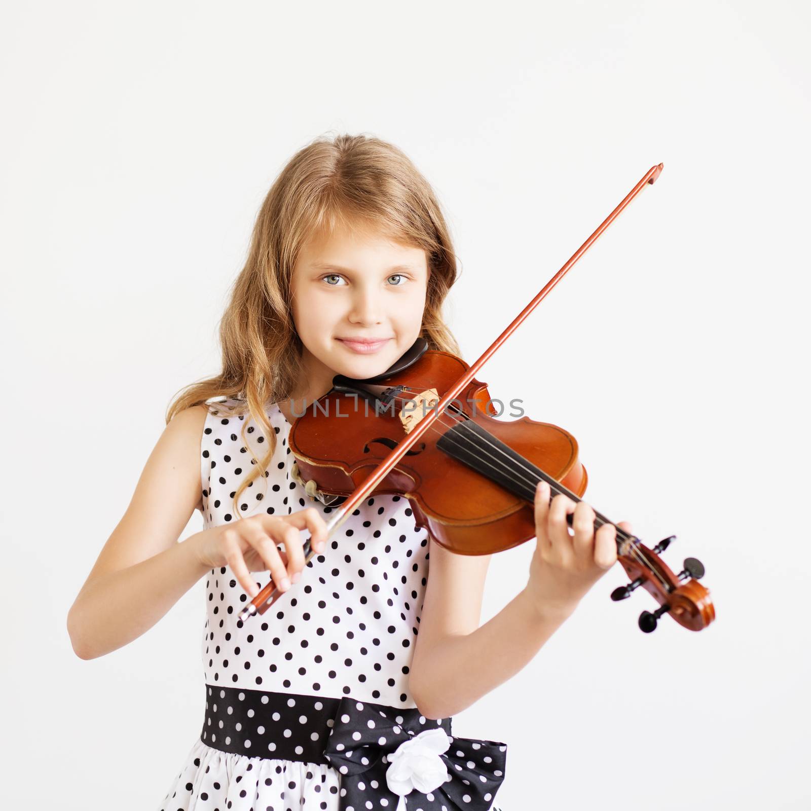 Portrait of the little violinist. Beautiful gifted little girl playing on violin against the white background