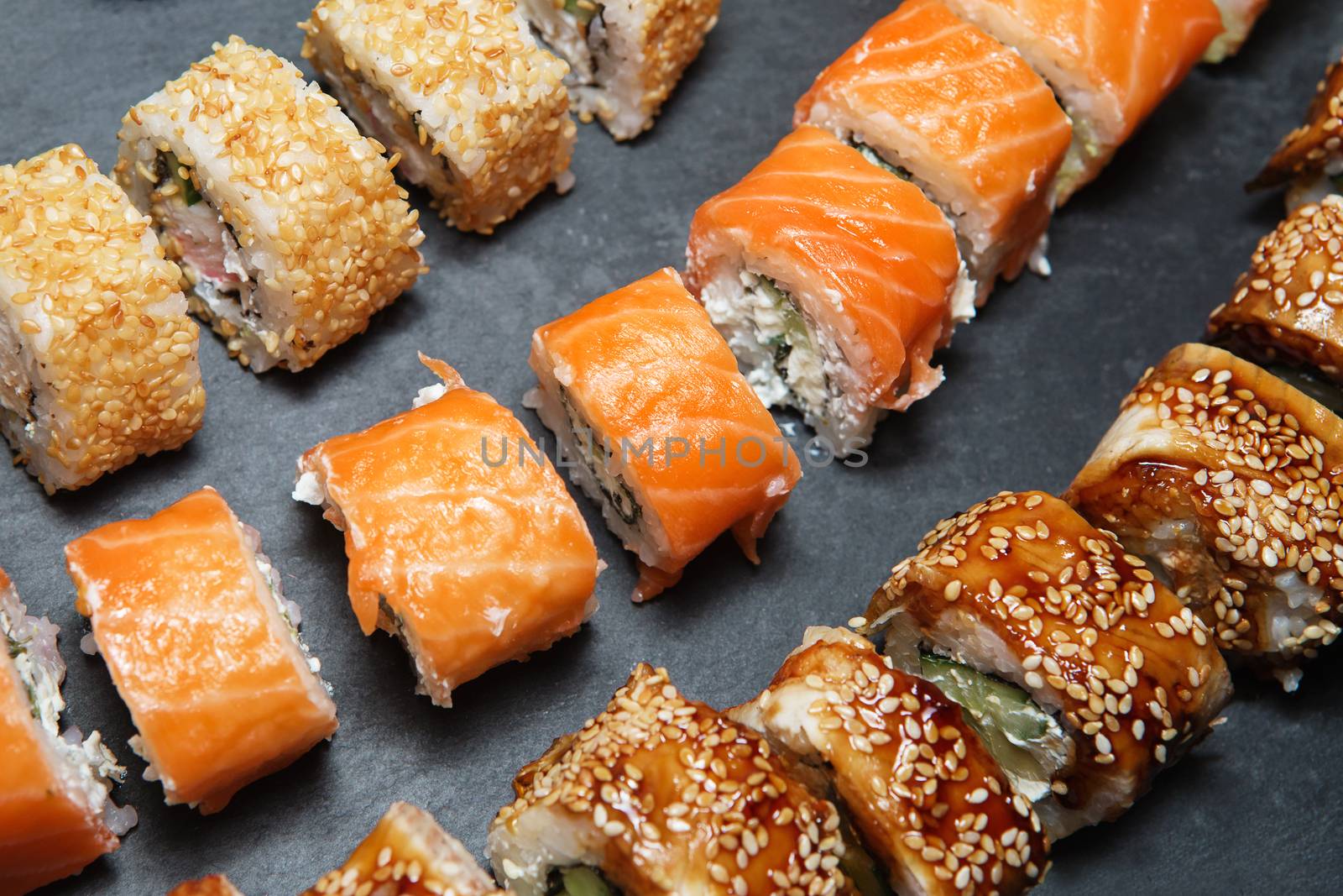 Philadelphia Roll, California Roll, Eel Avocado Roll on black slate tray background. Delicious rolls and sushi with eel, salmon, shrimp, cucumber and philadelphia. Various delicious Types of Sushi Rolls. Top view, flat lay